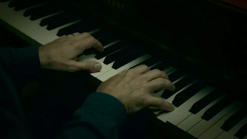 Hands on a piano in a dark room
